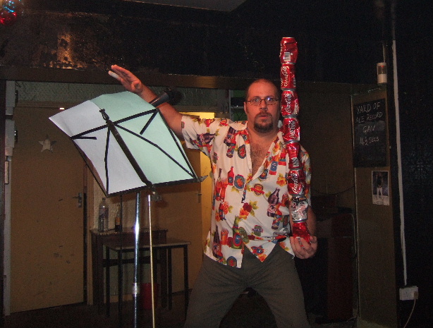 A fat man in a hawian shirt balancing a line of coke - cans